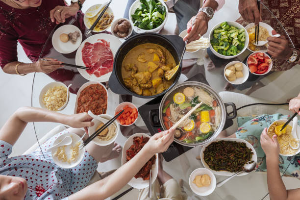 nouvel an chinois - vue aérienne d’une famille multiraciale prenant un repas de retrouvailles - cuisine fusion photos et images de collection