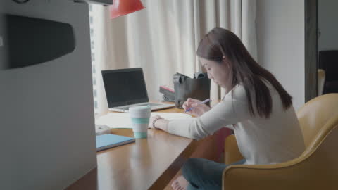 Southeast Woman working from home using laptop and notepad - Entrepreneurship concepts