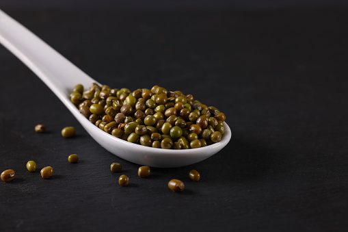 Green Lentils on a black slate platter. High resolution image 45Mp taken with Canon EOS R5 and associate macro lens