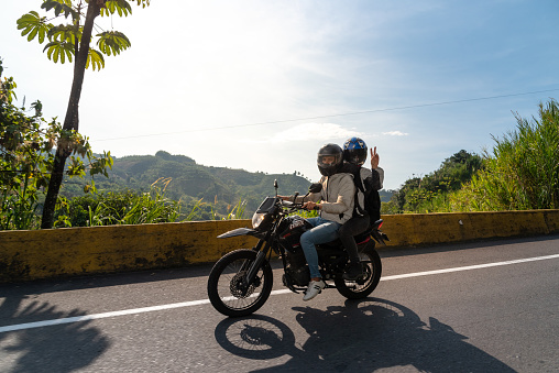 Couple on a motorcycle on a rural road in tropical climate. Caldas. Colombia. February 2, 2022.