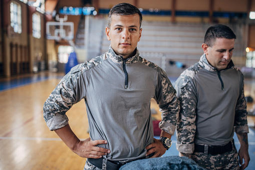 Two people, soldiers on humanitarian aid preparing donations for civilians in school gymnasium, after natural disaster happened in city.