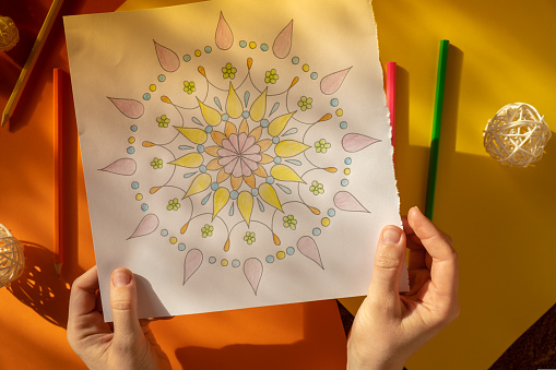 Woman coloring antistress page. Female hand painting mandala. Female painting mandalas to combat stress. Relaxing hobby mental wellbeing and art therapy. Woman paints sketch, meditative process of coloring pages. Self expression by art
