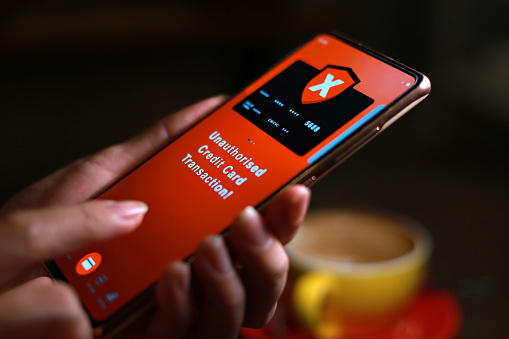 A woman receiving an alert message from bank regarding unauthorised credit card transaction on her phone. Unauthorised use of is a transaction involving the charging of expenses/purchase of goods and services without the consent of the cardholder