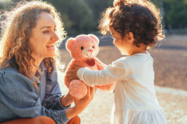 Mother giving a teddy bear to her doughter