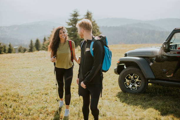 istock Smiling couple walking with backpacks over green hills 1419611372