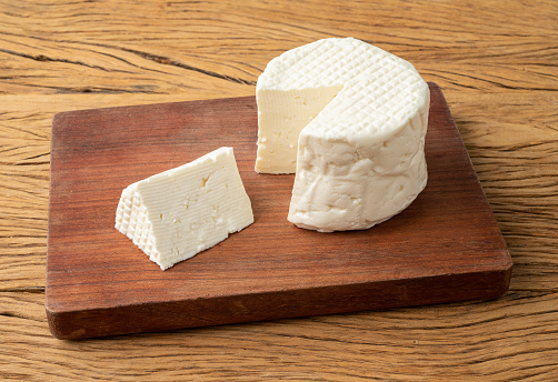 Frescal cheese, typical brazilian fresh white cheese with slice over wooden table.