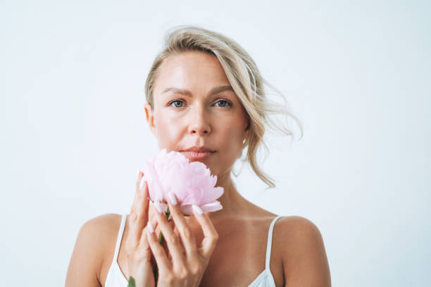 Beauty portrait of blonde hair smiling young woman with pink peony in hand isolated on white background Beauty portrait of blonde hair smiling young woman with pink peony in hand isolated on white background caucasian human face women freshness stock pictures, royalty-free photos & images