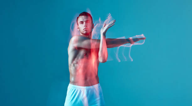 istock A young athletic, pumped-up man does a warm-up. A man with a bare torso and white shorts on a blue background. 1419615963