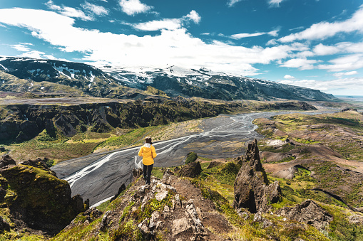 Majestic scenery of Valahnukur viewpoint with female hiker standing on peak and krossa river through in icelandic highlands at Thorsmork, Iceland