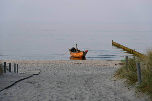 vecchia barca a remi in legno ormeggiata sulla spiaggia del mar baltico al crepuscolo - rowboat nautical vessel usedom sand foto e immagini stock