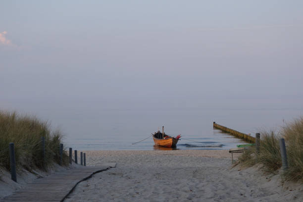 vecchia barca a remi in legno ormeggiata sulla spiaggia del mar baltico al crepuscolo - rowboat nautical vessel usedom sand foto e immagini stock