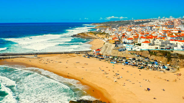 Drone view to Beautiful resort touristic town on ocean background. Aerial view - Beautiful travel destination with sandy beach. Tourist beach for surfing while vacation at Ericeira, in Summer. stock photo