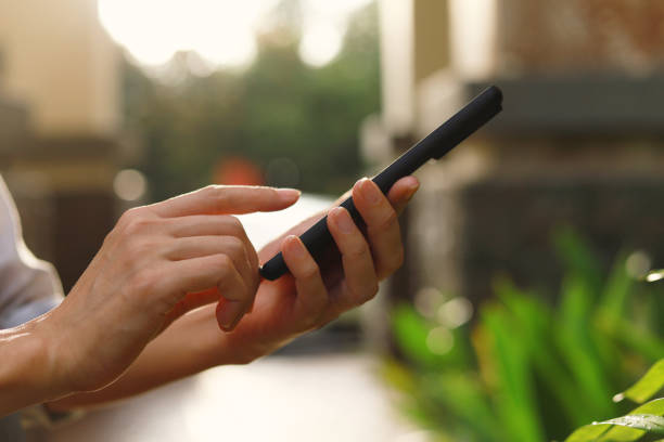 Cropped image of hands holding mobile or smart phone in the garden