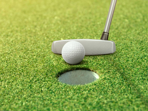 istock Golf ball and putter is on green grass next to golf hole 1419622553