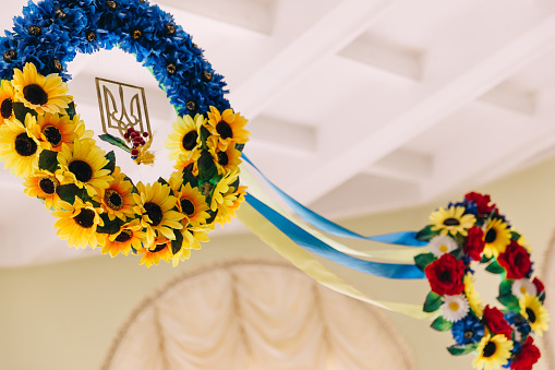 Ukrainian national symbols. wreaths of beautiful flowers and coat of arms in the center. wreaths are connected by ribbons near the ceiling.