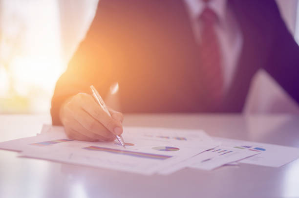 Male manager putting his ideas and writing business plan at workplace,man holding pens and papers, making notes in documents, on the table in office,vintage color,morning light ,selective focus. gerente masculino poniendo sus ideas y escribiendo plan de negocios en el lugar de trabajo, hombre sosteniendo bolígrafos y papeles, haciendo notas en documentos, en la mesa en la oficina, color vintage, luz de la mañana, enfoque selectivo.