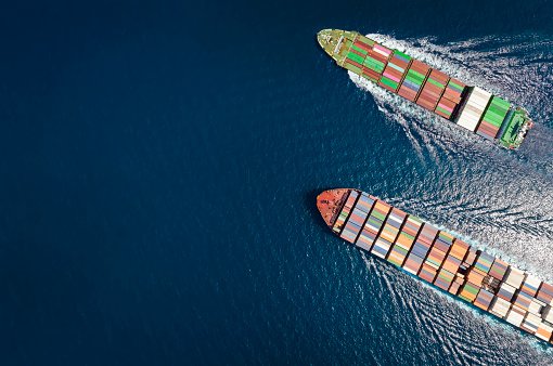 High aerial top down view of two container cargo ships traveling over open ocean