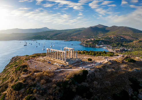 Aerial view of the beach and Temple of Poseidon at Cape Sounion at the edge of Attica, Greece, during summer sunset time