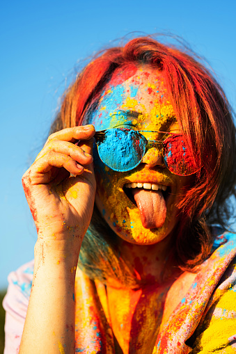 Woman covered in holi powder against blue sky. Holi colours festival.