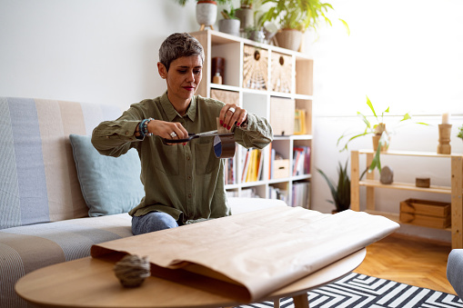 Woman, an online seller, packaging a painting for shipping.