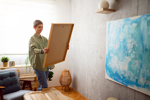 Woman preparing a new painting to hang it on the wall.