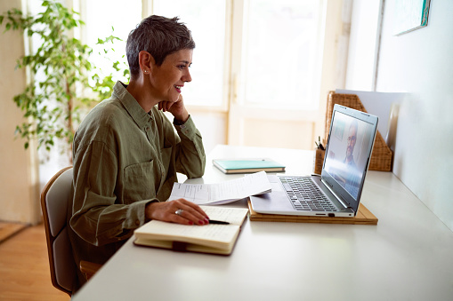 Mujer siguiendo cursos en línea en su computadora portátil en casa photo