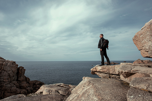 Side view full length Man on the rocks at coastline  admiring the ocean