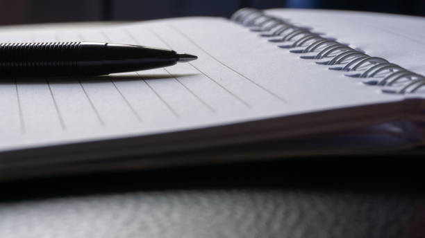 istock Black ink pen on a note book. pen on the office desk 1419636022