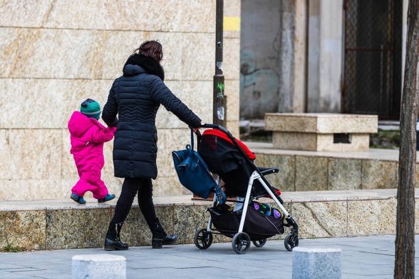 Single mom with child pushing baby stroller in Bucharest, Romania, 2022