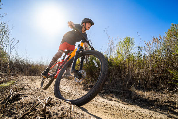 Um menino montando sua mountain bike em pastagens - foto de acervo