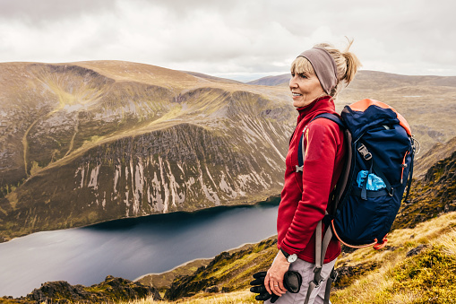 Woman near the summit of a Scottish Munro called Sgor Gaoith, near the resort of Aviemore, Scotland in summer. The ridge falls steeply through 500 metres of cliffs to the loch below.