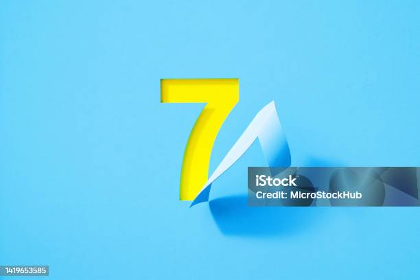Blue Number Seven Folding On Yellow Background Stock Photo - Download Image Now - Number 7, Paper, Adhesive Note