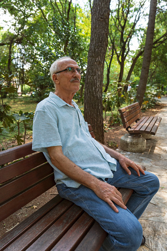 Senior man relaxing at park bench