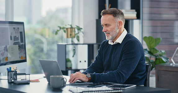 Mature ceo, typing and working on laptop in his office. Corporate business man busy using computer to email colleagues. Committed and professional worker uses tech for efficient communication.