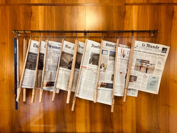 Sils Maria, Swizerland - August, 24 - 2022: International newspapers hanging at a wooden wall in a public library.
