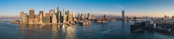 Lower Manhattan from the East River, panoramic view at sunrise. Brooklyn Bridge and Manhattan Bridge at the distance. Extra-large high resolution stitched panorama.