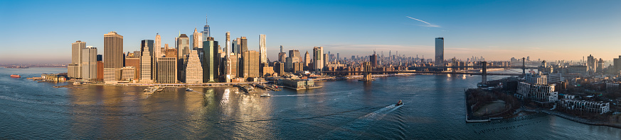 Panoramic view of Lower Manhattan from the East River in the early, foggy, winter morning. Brooklyn Bridge and Manhattan Bridge at the distance.