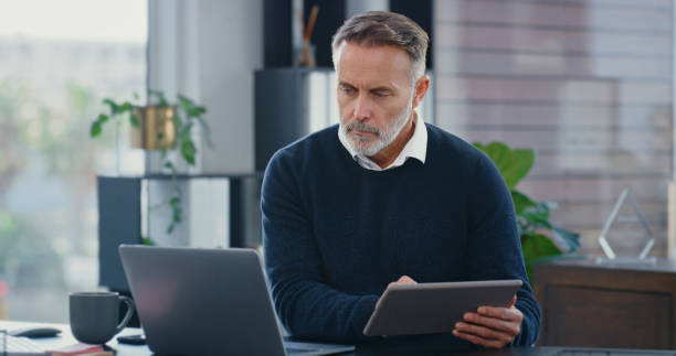 istock Thinking business man, manager and mature expert planning analytics, strategy and idea with tablet, laptop and internet in agency. Company ceo leader working with vision and growth mindset in office 1419667141
