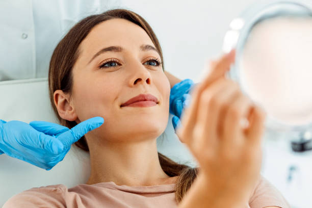 Beautiful smiling Woman having Facial Treatment looking at mirror Young Beautiful Woman Having Various Facial Treatment human mouth stock pictures, royalty-free photos & images