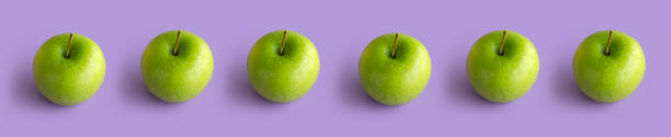 istock Green apples on purple background 1419672633