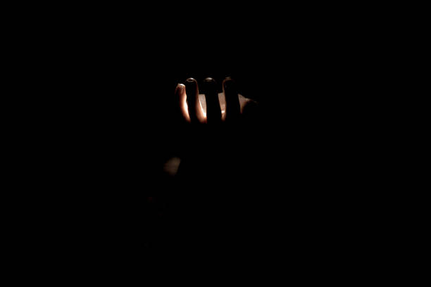 istock Woman's hand in the dark with weak light, fear 1419678873
