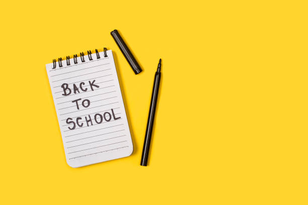 istock Back to school write in a lined notepad and a black marker on a yellow background 1419680912