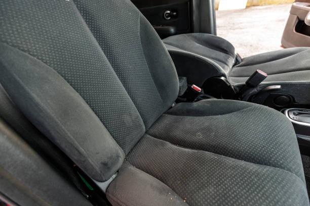 Dirty passenger seat with stains and crumbs before professional cleaning service.