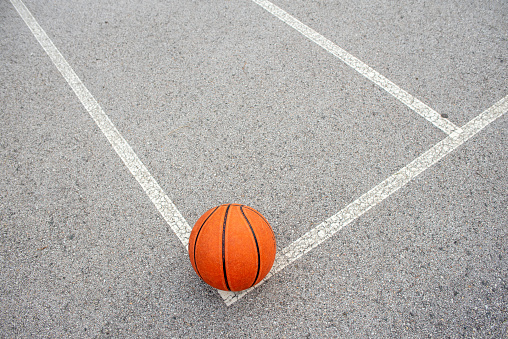 Orange ball in basketball court in top view in street