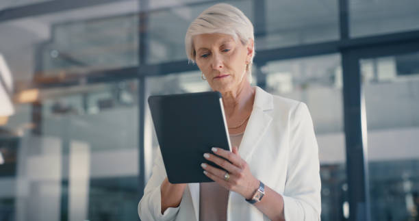 istock Online, web and internet research on a digital tablet with a senior, corporate and executive woman. Ceo office business management employee working and planning a advertising marketing strategy 1419689516