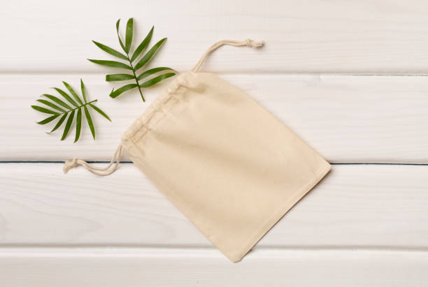 istock Small eco sack with green leaves on color background. Top view 1419695509