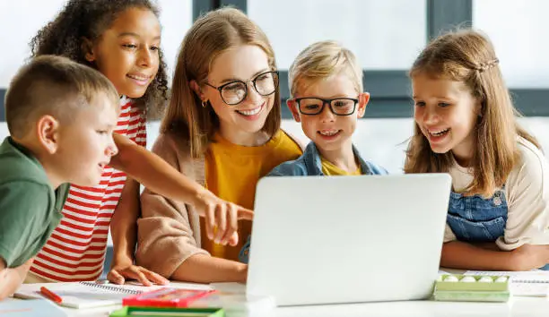 Photo of Teacher and pupils using laptop