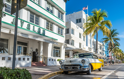 Miami, USA - August 31, 2022: View of a beautiful classic old American car from the 50s, at the doors of an art deco hotel on Ocean Drive, in Miami Beach, Florida.