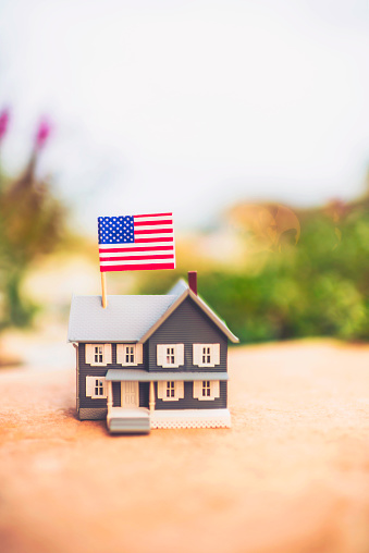 Small house outdoors with American flag. New home and home ownership concept