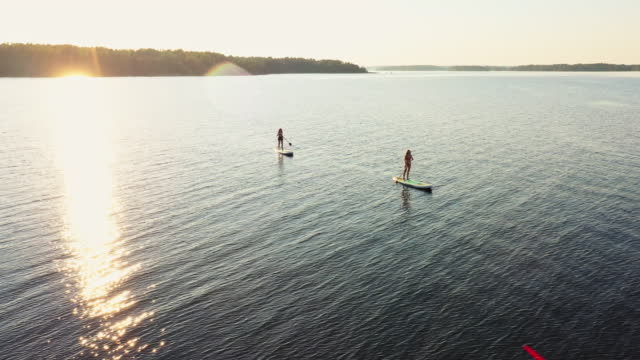 Two young woman paddleboarding at the lake